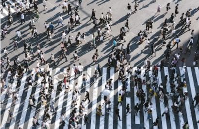 Lots of pedestrians walking across a pedestrian crossing in a busy road