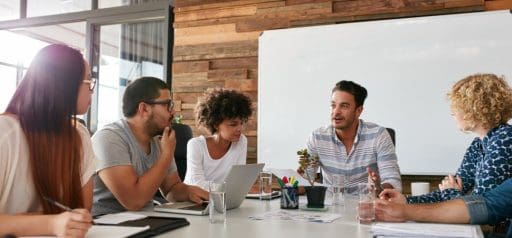 A Group of people sitting at a desk in a meeting room having a discussion