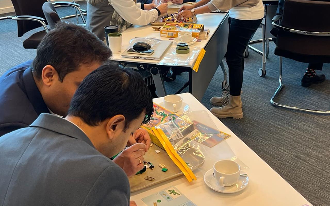 Two men building lego in a workshop setting