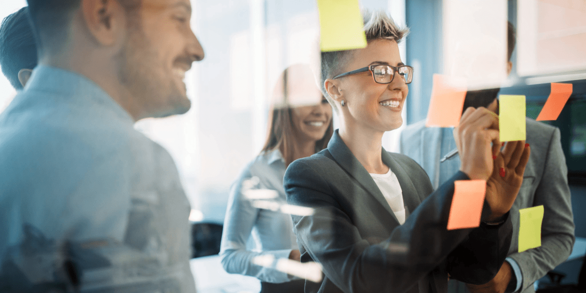Colleagues collaborating around a glass wall covered in sticky notes
