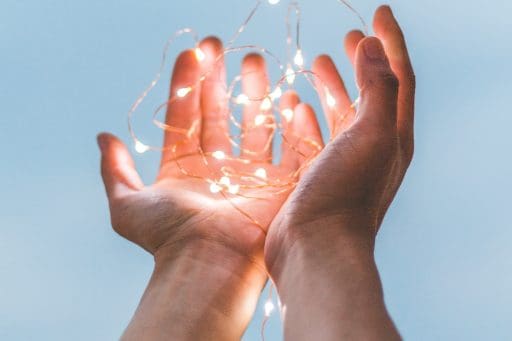 Two hands cupping a string of small fairy lights