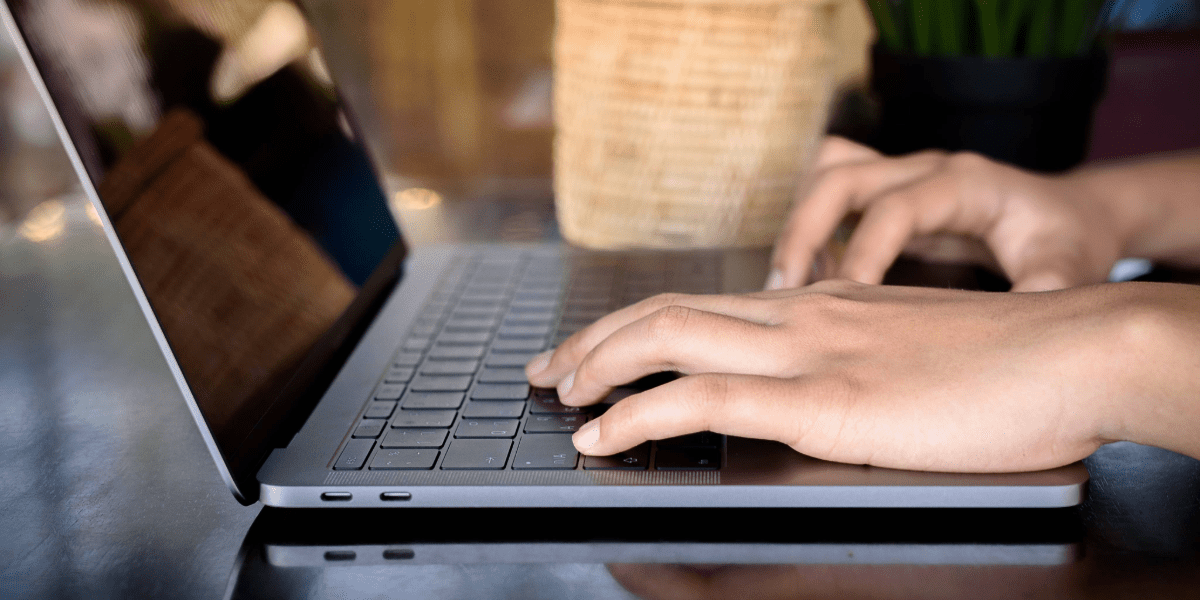 Hands typing on a laptop keyboard at a desk
